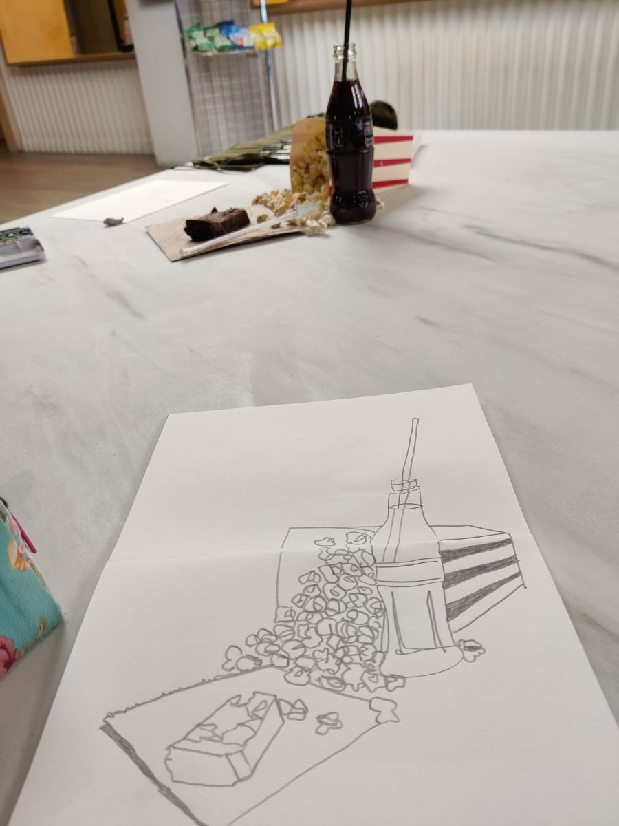 still life and pencil sketch of a glass bottle of coke with straw, box of popcorn, and chocolate brownie.