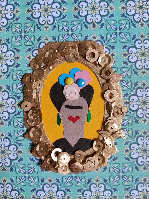 A paper collage portrait of a tiny Frida Kahlo, in a gold steampunk frame, on a turquoise tile background