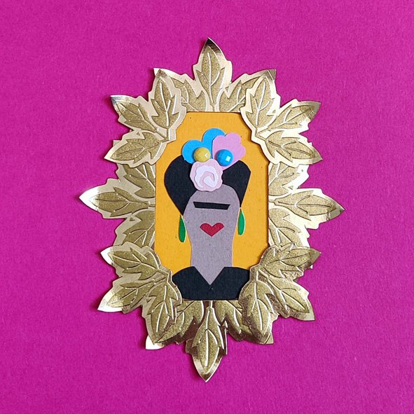 A tiny Frida Kahlo portrait made from cut paper collage. The portrait is in a tiny frame made from gold card leaves.