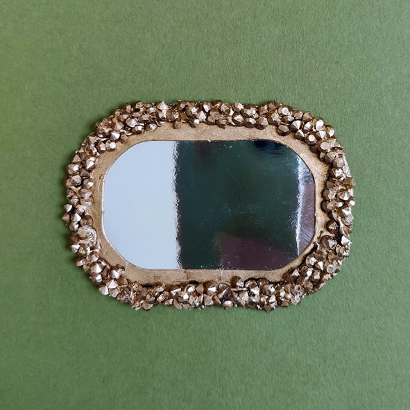 a 1:12 scale mirror made from card, tiny plastic gemstones, and gold paint.